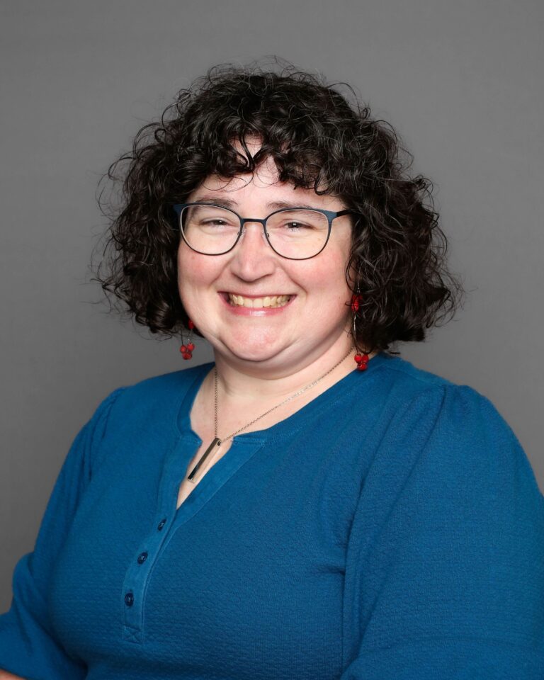 Smiling woman with curly hair and glasses