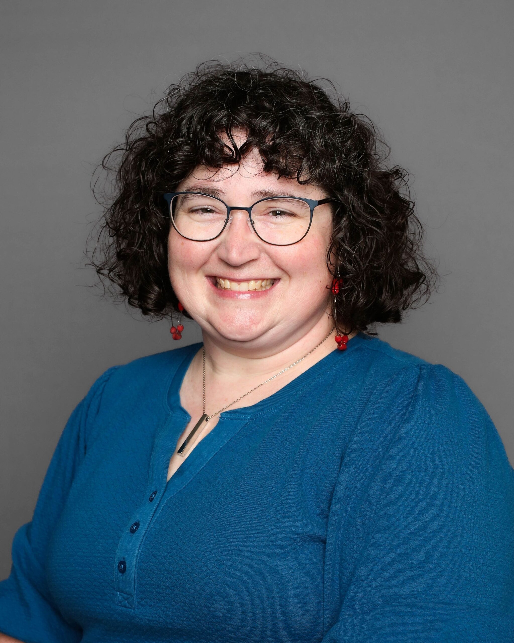Smiling woman with curly hair and glasses